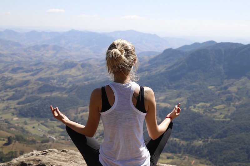 young woman meditating on the mountain top